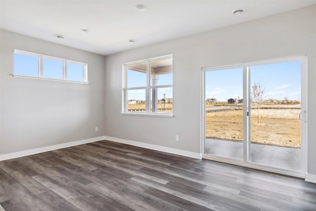 spare room with baseboards and dark wood-style flooring