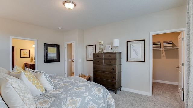 carpeted bedroom with a walk in closet, ensuite bath, baseboards, and a closet