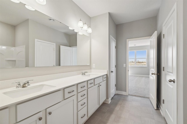 full bathroom with double vanity, baseboards, and a sink