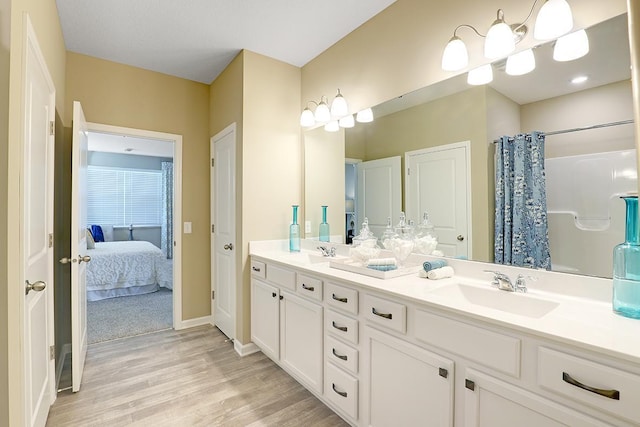 full bathroom with double vanity, wood finished floors, ensuite bathroom, and a sink