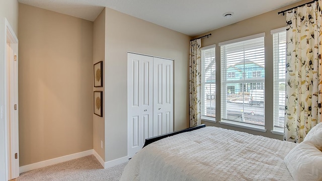 bedroom featuring a closet, light colored carpet, and baseboards