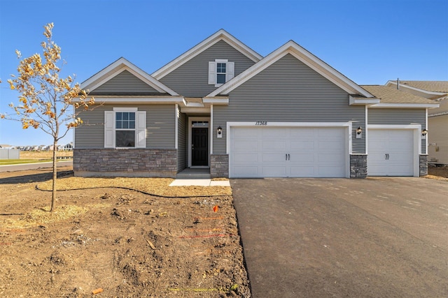 view of front of house with aphalt driveway, a garage, and stone siding