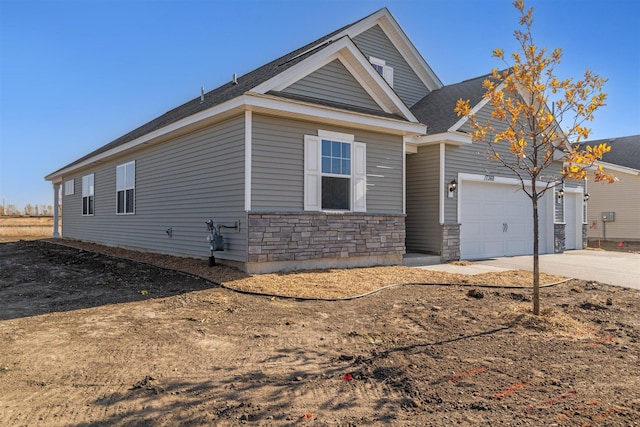 view of home's exterior with stone siding, an attached garage, and driveway