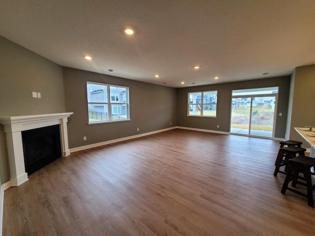 unfurnished living room with dark wood-type flooring, recessed lighting, a fireplace, and baseboards