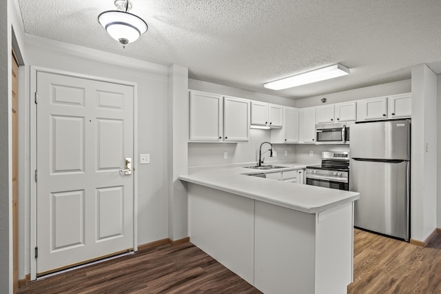 kitchen featuring light countertops, stainless steel appliances, dark wood-style floors, white cabinetry, and a sink