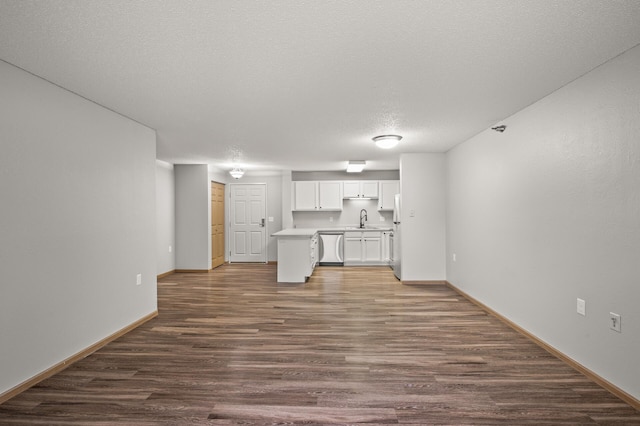 unfurnished living room featuring a textured ceiling, wood finished floors, baseboards, and a sink