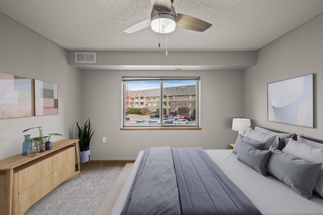 carpeted bedroom with a ceiling fan, baseboards, visible vents, and a textured ceiling