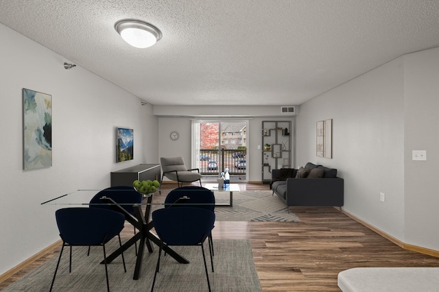 dining area with baseboards, wood finished floors, visible vents, and a textured ceiling