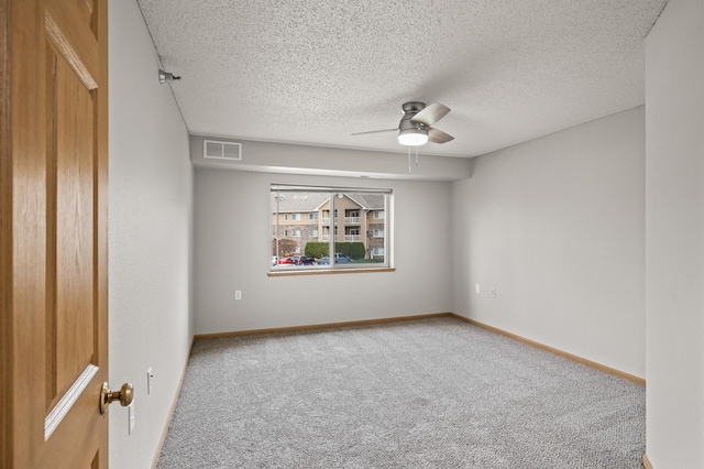 spare room featuring baseboards, visible vents, carpet floors, ceiling fan, and a textured ceiling