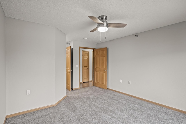 empty room featuring baseboards, carpet floors, a textured ceiling, and a ceiling fan