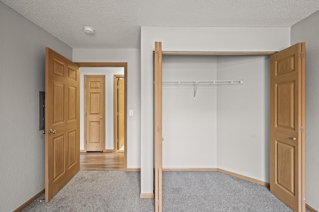 unfurnished bedroom with a closet, a textured ceiling, baseboards, and carpet floors