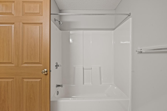 bathroom with a textured ceiling and washtub / shower combination