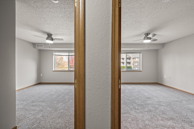 empty room featuring carpet flooring, ceiling fan, baseboards, and visible vents