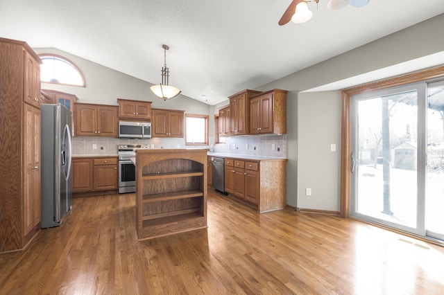 kitchen featuring visible vents, a kitchen island, light countertops, appliances with stainless steel finishes, and open shelves