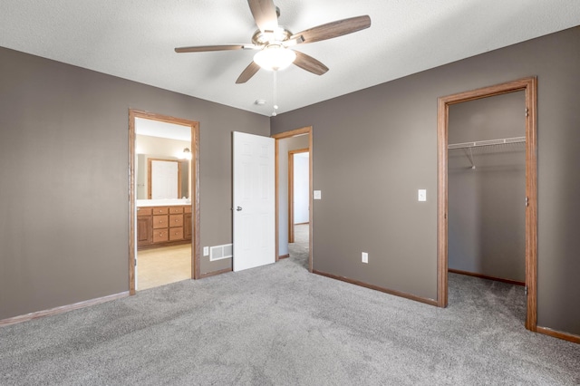 unfurnished bedroom with a spacious closet, visible vents, baseboards, carpet, and a closet