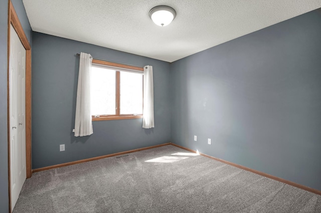 empty room featuring visible vents, baseboards, a textured ceiling, and carpet flooring