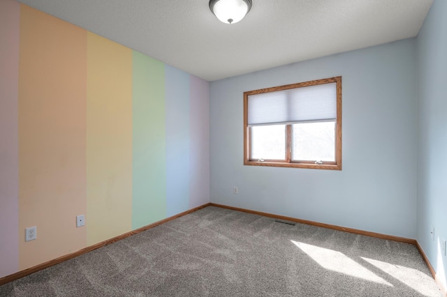 carpeted spare room featuring visible vents and baseboards