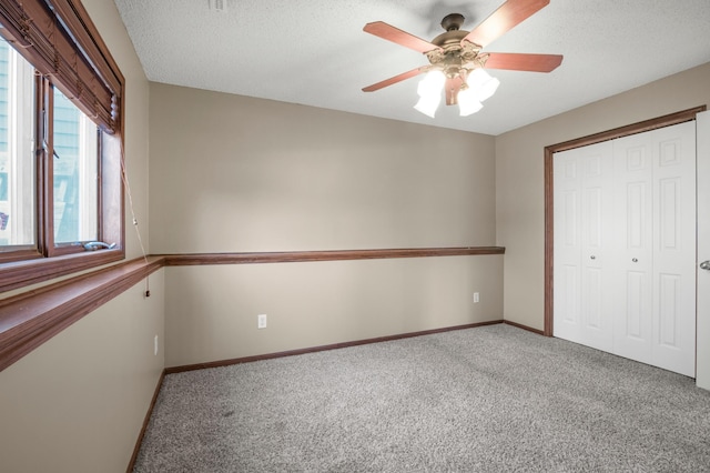 unfurnished bedroom featuring a closet, carpet flooring, a textured ceiling, and baseboards