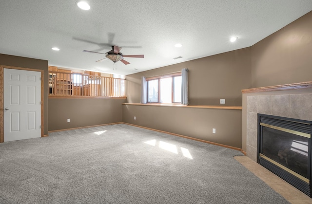 unfurnished living room featuring visible vents, a ceiling fan, carpet flooring, baseboards, and a tile fireplace