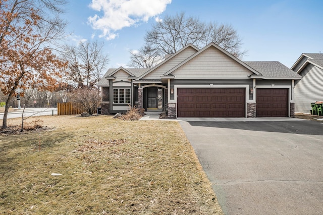 craftsman-style house with driveway, a front lawn, fence, roof with shingles, and an attached garage