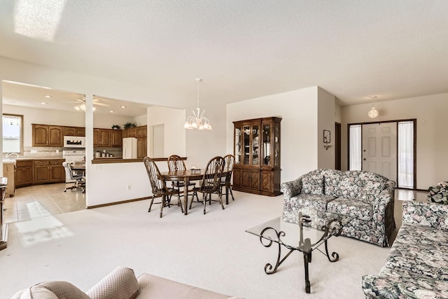 dining space featuring light tile patterned floors, ceiling fan with notable chandelier, light colored carpet, and a textured ceiling