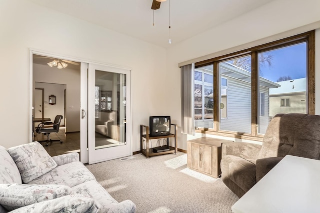 carpeted living room featuring baseboards and a ceiling fan