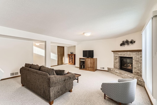 living room with visible vents, carpet flooring, a brick fireplace, and a textured ceiling