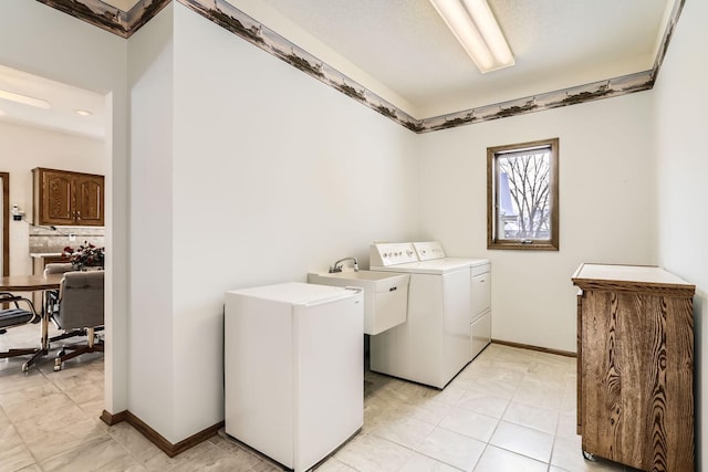 laundry area featuring laundry area, washing machine and dryer, baseboards, and a sink