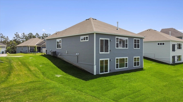 rear view of property with a lawn, central AC, and roof with shingles