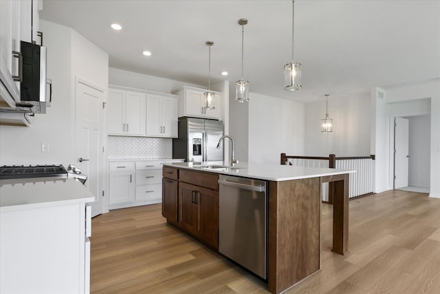 kitchen featuring a sink, stainless steel appliances, light wood-style floors, and light countertops