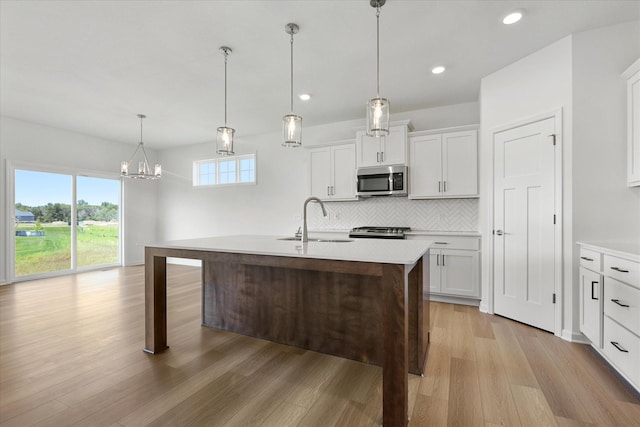 kitchen featuring light wood finished floors, light countertops, decorative backsplash, stainless steel appliances, and a sink