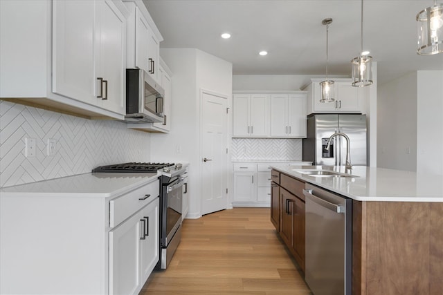 kitchen with a center island with sink, stainless steel appliances, light countertops, and light wood-style floors