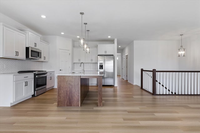 kitchen featuring white cabinetry, stainless steel appliances, light wood-type flooring, and light countertops