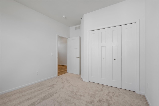 unfurnished bedroom with a closet, visible vents, baseboards, and carpet