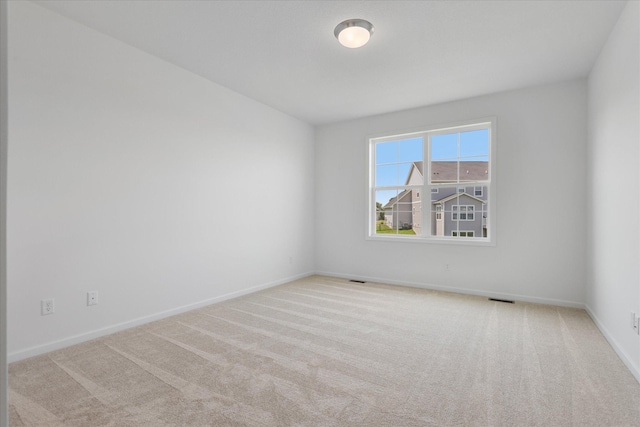 spare room with carpet flooring, baseboards, and visible vents