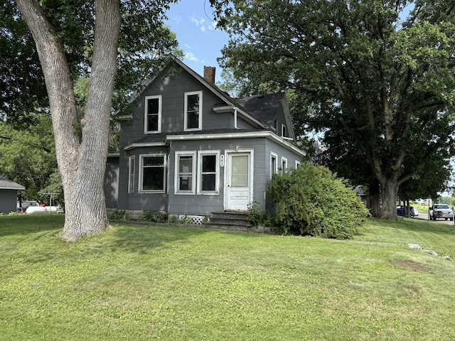 902 Pacific Ave, Kerkhoven, MN 56252 - view of front of house featuring entry steps, a chimney, a front lawn, and roof with shingles