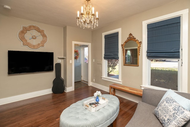 living area with a wealth of natural light, baseboards, an inviting chandelier, and wood finished floors