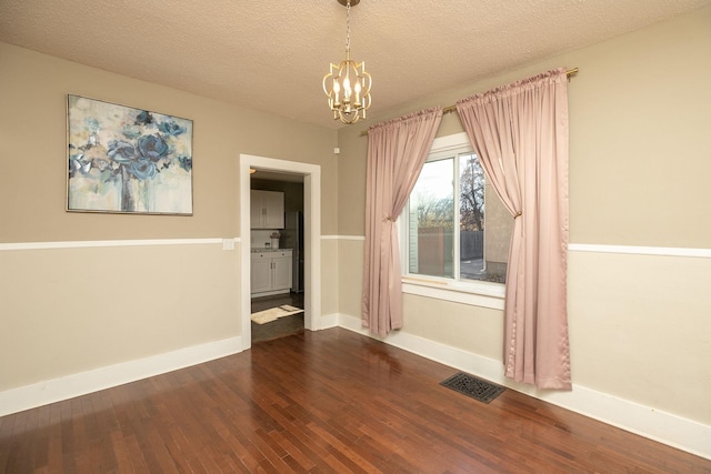 unfurnished dining area with visible vents, baseboards, an inviting chandelier, a textured ceiling, and dark wood-style flooring