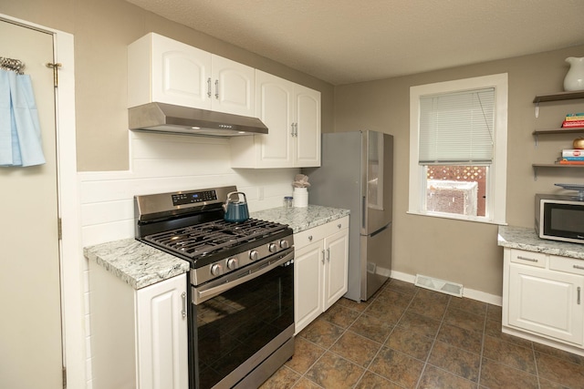 kitchen with visible vents, under cabinet range hood, light stone counters, appliances with stainless steel finishes, and white cabinets