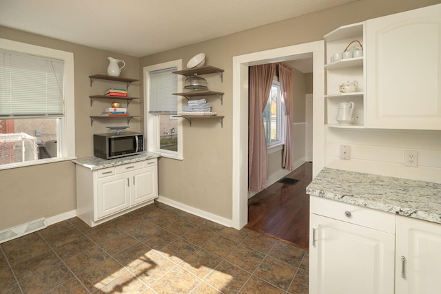 kitchen featuring stainless steel microwave, baseboards, visible vents, and open shelves