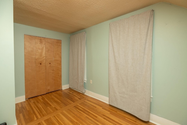 unfurnished bedroom with wood finished floors, baseboards, and a textured ceiling