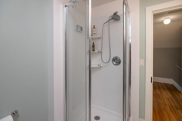 bathroom featuring a stall shower, baseboards, and wood finished floors