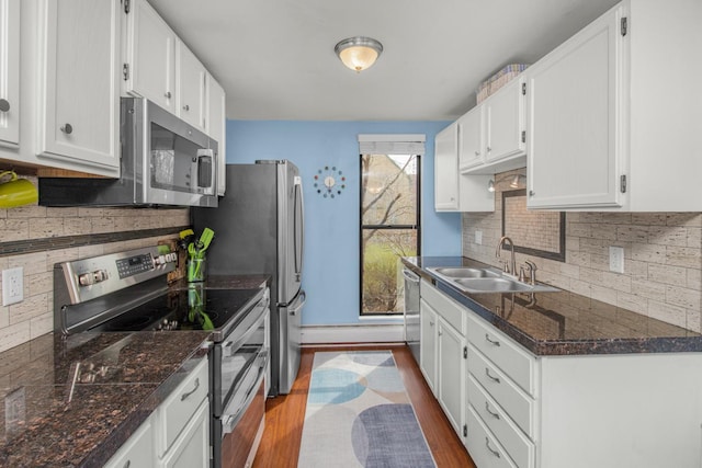 kitchen featuring tasteful backsplash, a sink, appliances with stainless steel finishes, white cabinets, and dark wood-style flooring