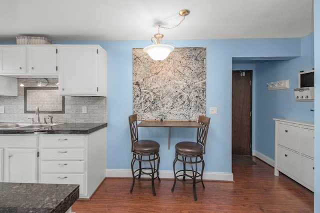 kitchen with a sink, tasteful backsplash, white cabinets, and dark wood-style flooring