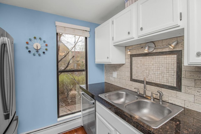 kitchen featuring white cabinetry, dark countertops, appliances with stainless steel finishes, and a sink