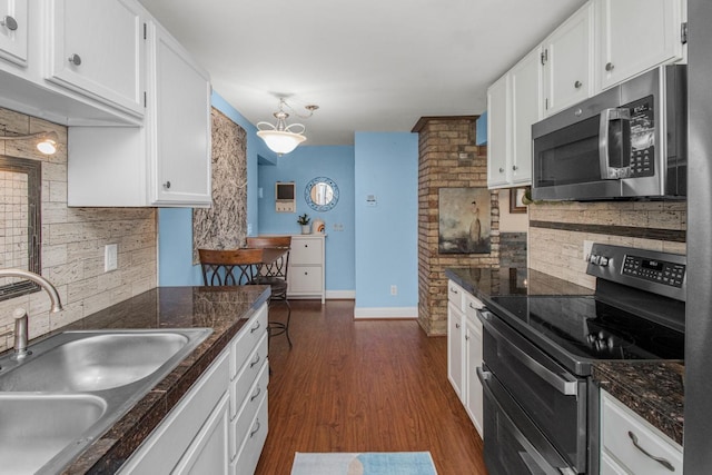 kitchen with decorative backsplash, white cabinetry, stainless steel appliances, and a sink