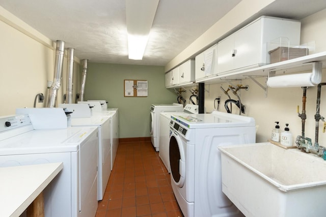 laundry room with baseboards, washing machine and clothes dryer, dark tile patterned flooring, cabinet space, and a sink