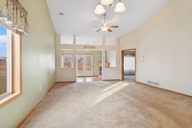 unfurnished living room featuring visible vents, carpet flooring, high vaulted ceiling, and baseboards