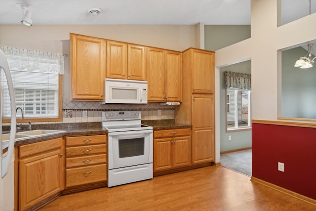 kitchen featuring dark countertops, white appliances, light wood-style floors, decorative backsplash, and vaulted ceiling