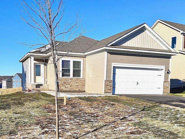 view of front of property featuring board and batten siding, entry steps, a garage, stone siding, and driveway